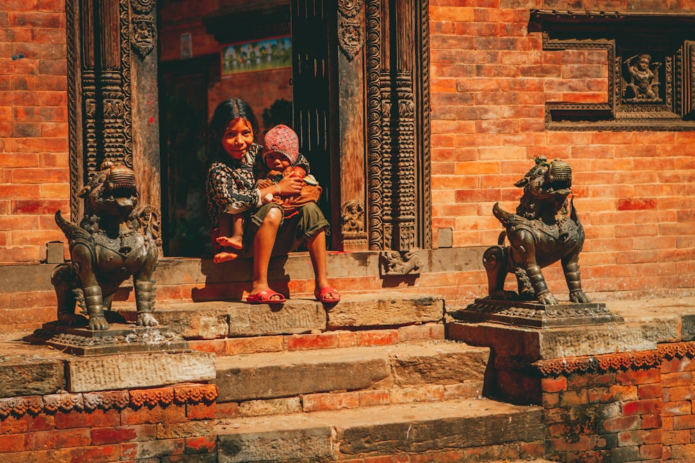 two little girls sitting on the steps of a building