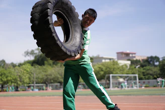 man in green and white long sleeve shirt and green pants holding black tire