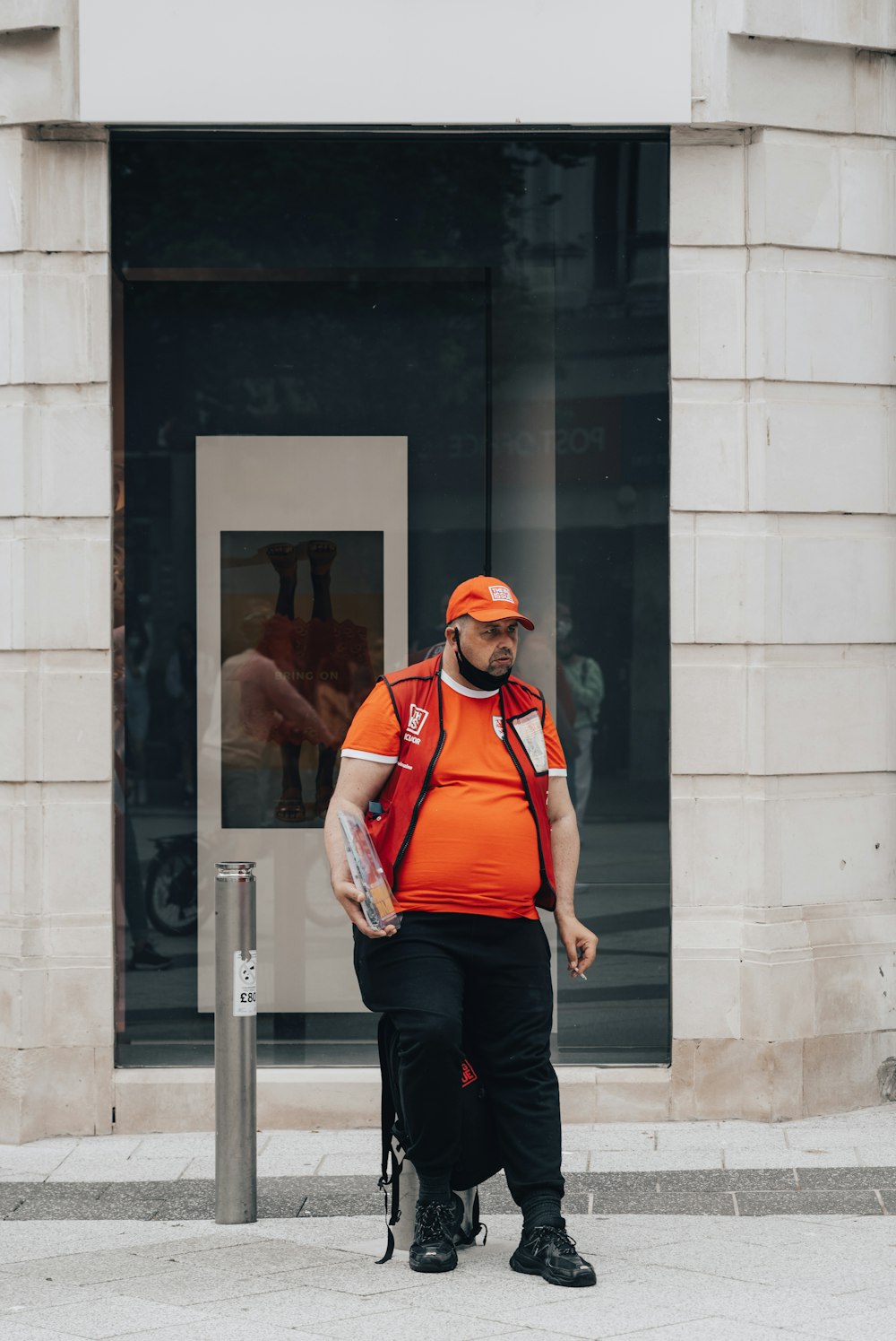 a man in an orange vest is walking down the street