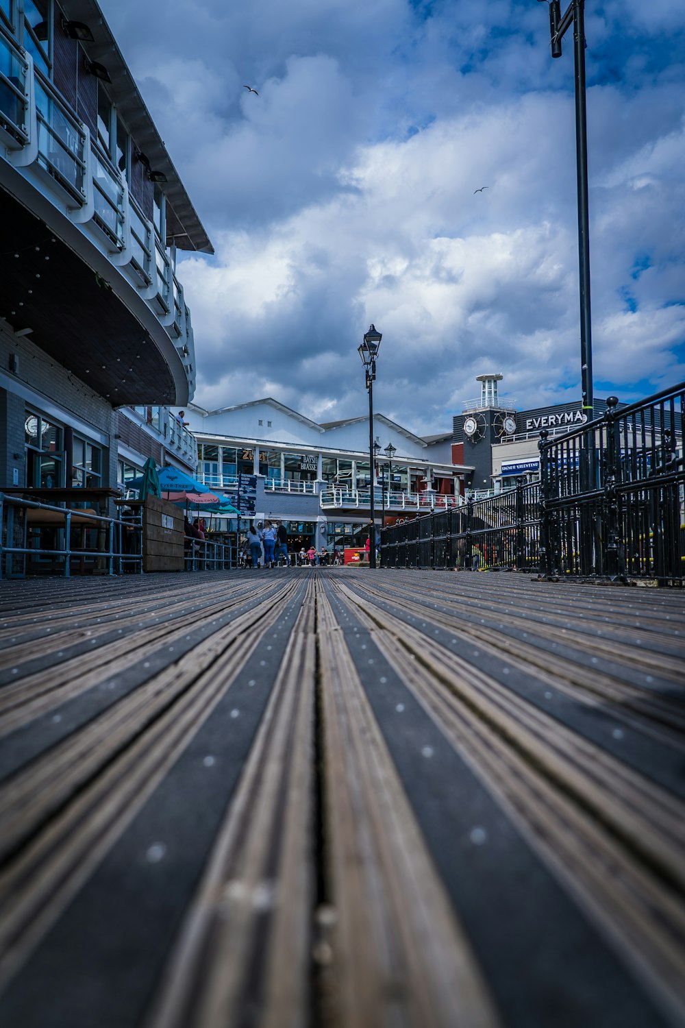 a wooden boardwalk in front of a building under a cloudy sky