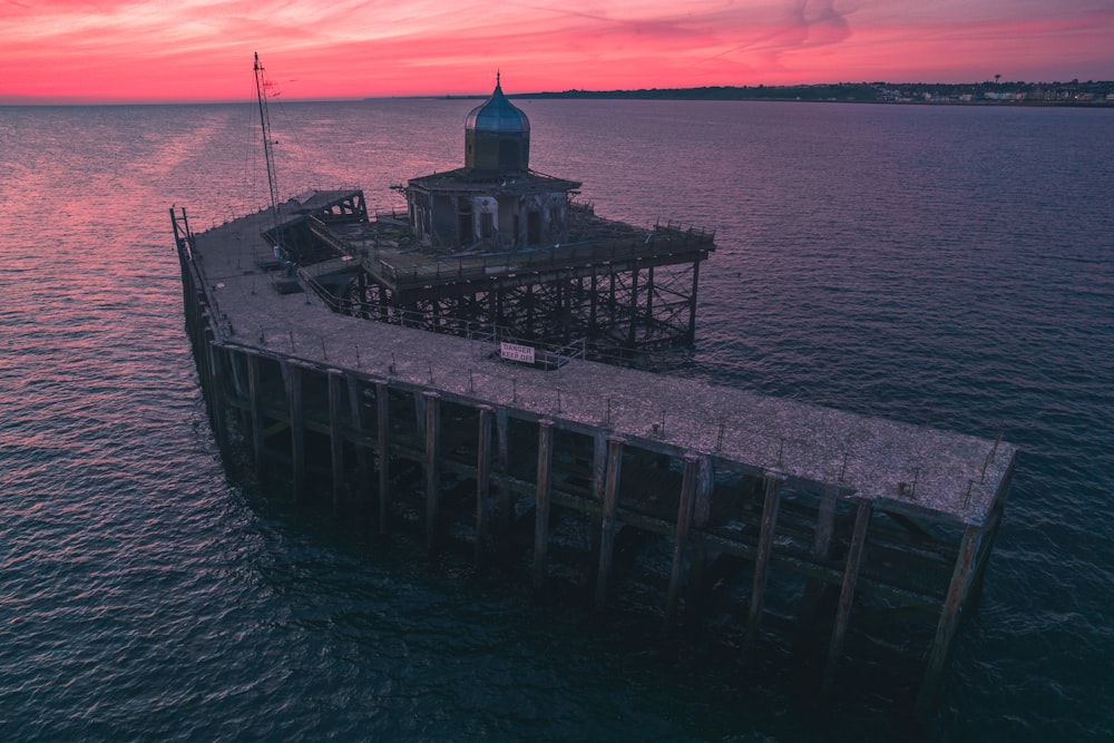 a pier with a building on it in the middle of the ocean