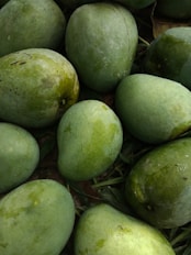 a pile of green fruit sitting on top of grass