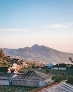 houses near mountain under white clouds during daytime