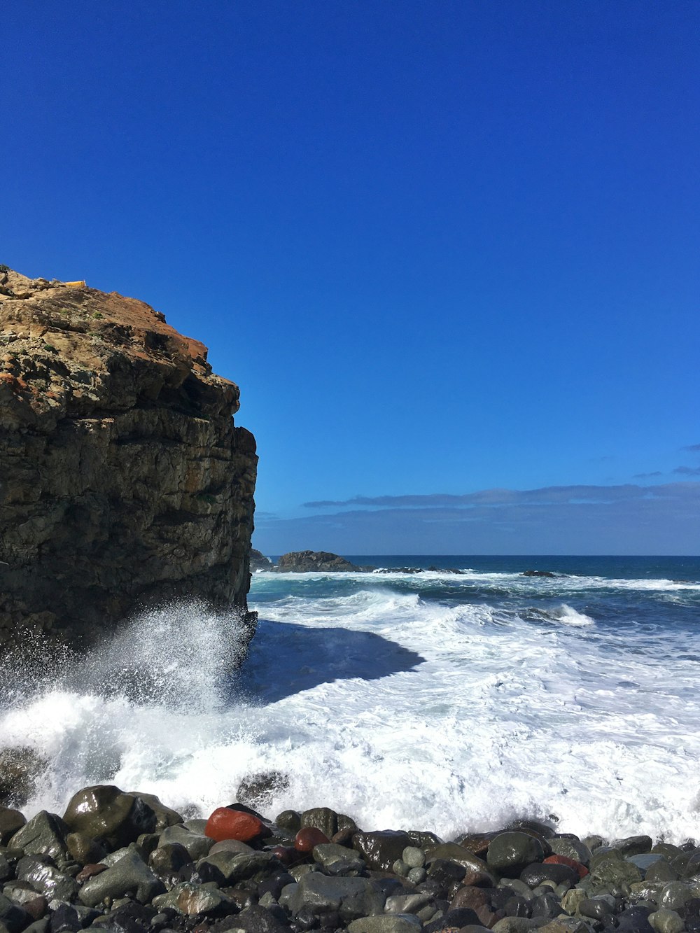 brown rock formation on sea under blue sky during daytime