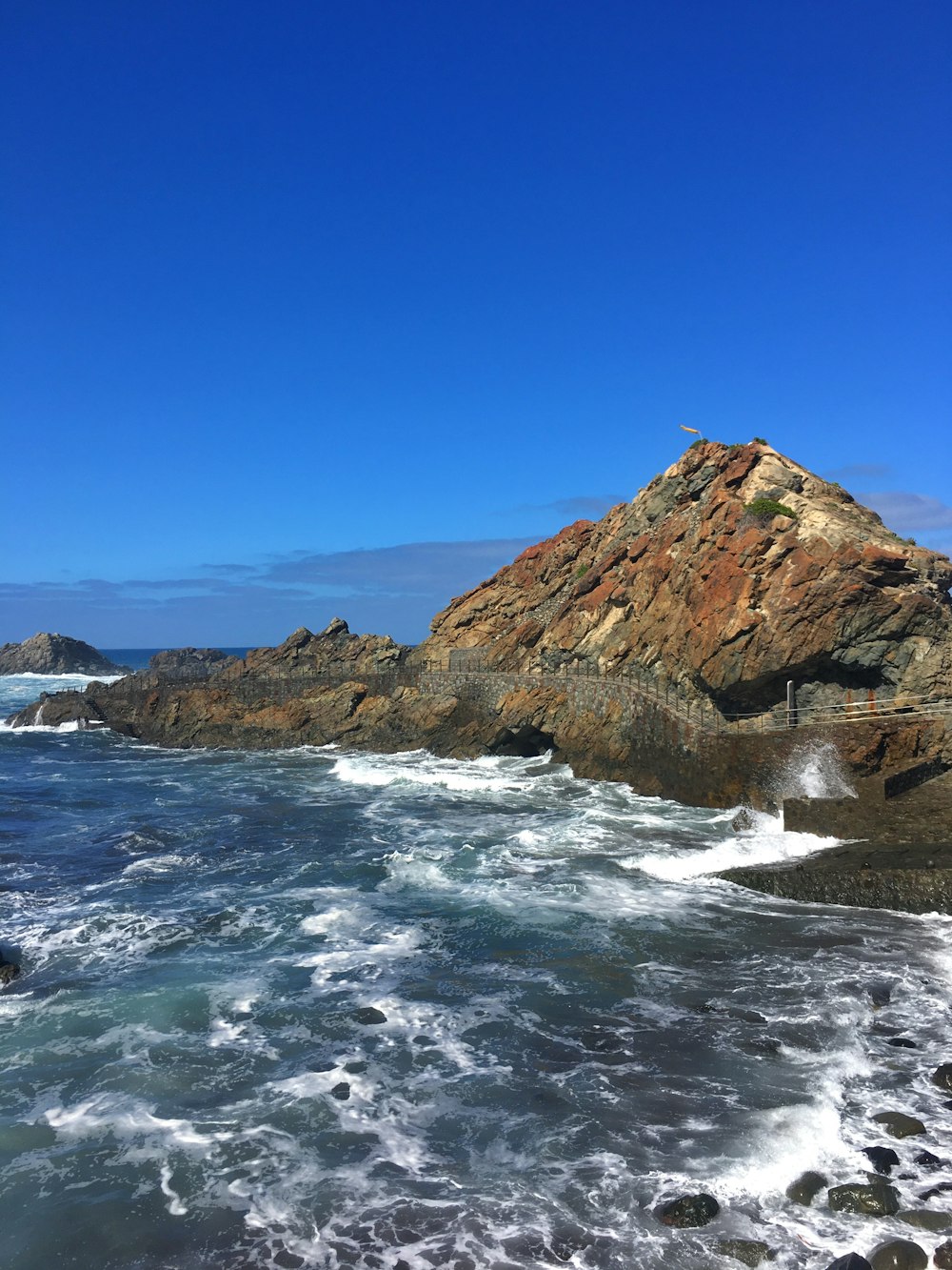 brown rock formation on sea under blue sky during daytime