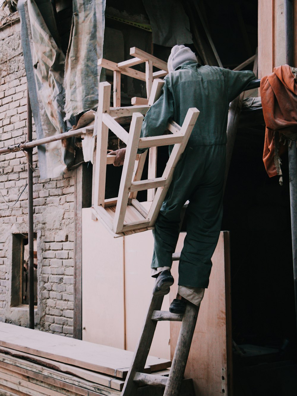 a man in a green coverall climbing up a ladder