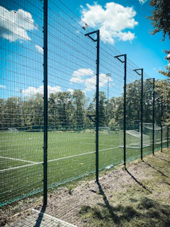 Parents watching their children play football in a secure, fenced sports ground with vibrant surroundings.