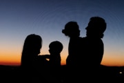 silhouette of 2 women and man standing during sunset