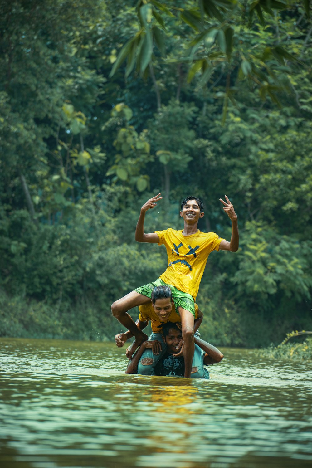 2 boys in yellow shirt jumping on water during daytime