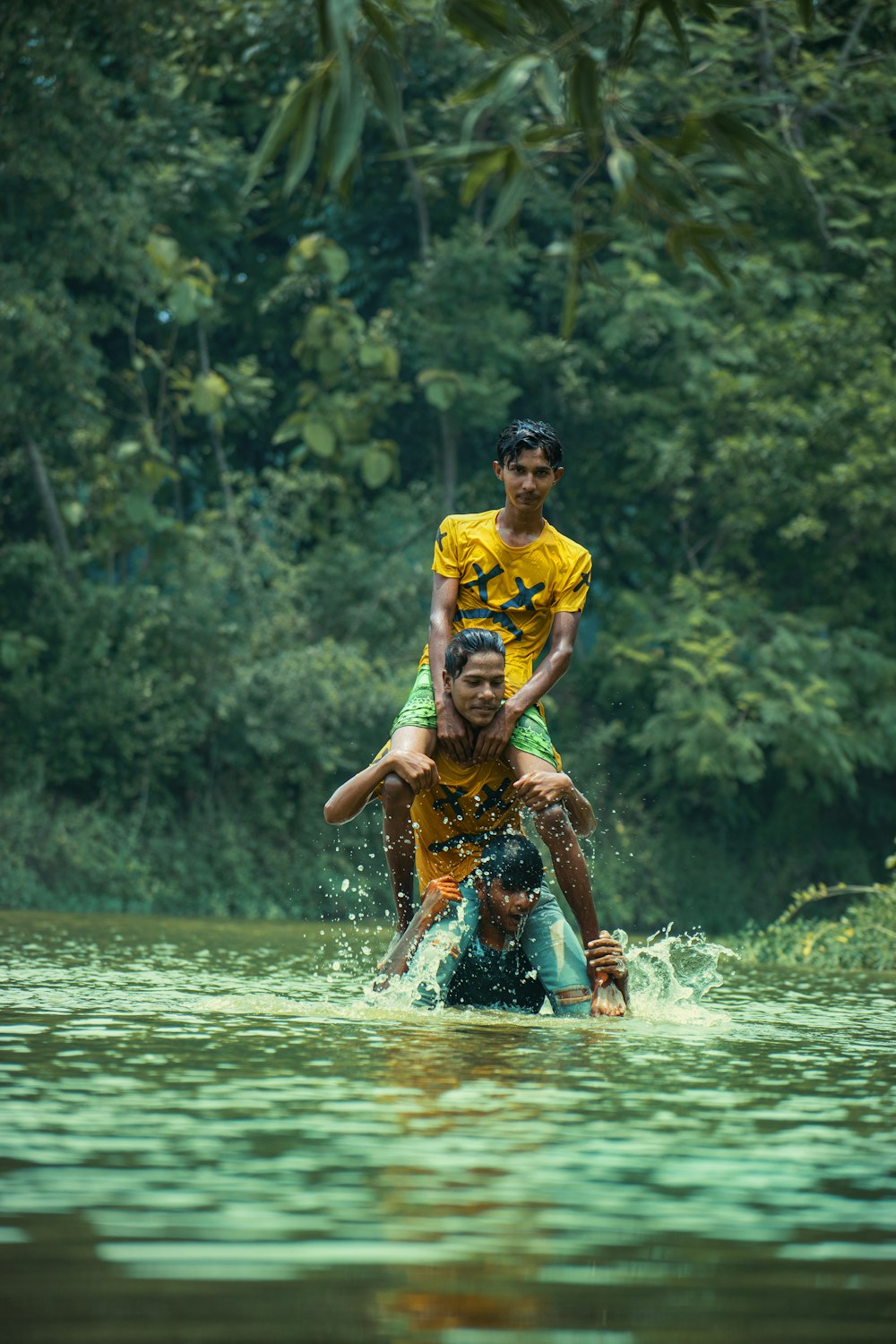 man in yellow shirt and blue shorts running on water during daytime