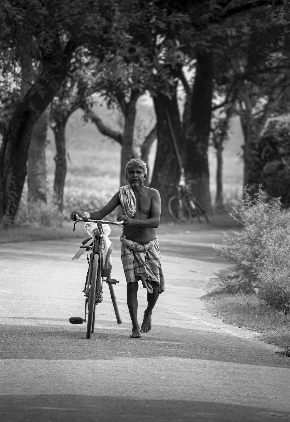 grayscale photo of woman riding bicycle on road