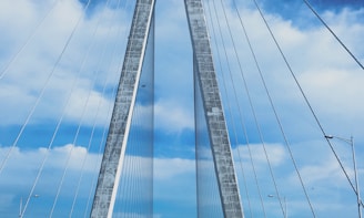 A towering cable-stayed bridge under construction against a blue sky.