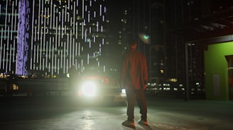 A locksmith technician unlocking a car door at night with bright city lights in the background