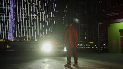 Nighttime city backdrop with a Velora vehicle waiting under bright airport lights.