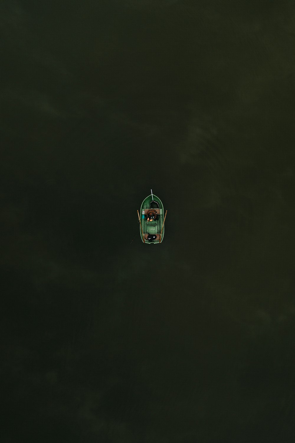 a small green boat floating on top of a body of water