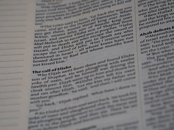 A close-up shot of an open book showing text in two columns. The text appears to be printed with black ink on white paper. The left margin contains lines for notes, and the text is organized with headings and paragraphs, typically seen in a textbook or scripture.