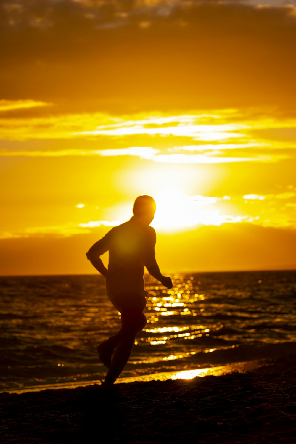 silhouette of man running on beach during sunset