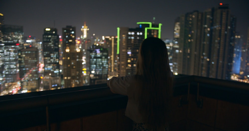 a woman looking out over a city at night