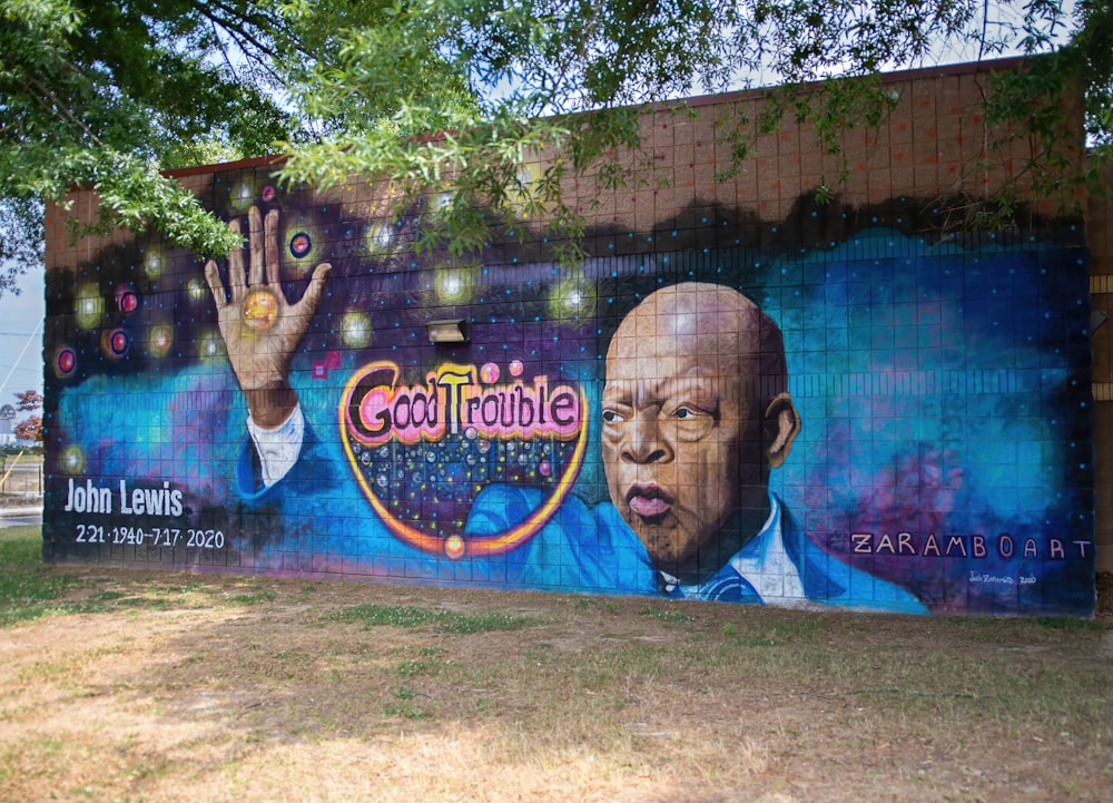 man in blue shirt standing near wall with graffiti