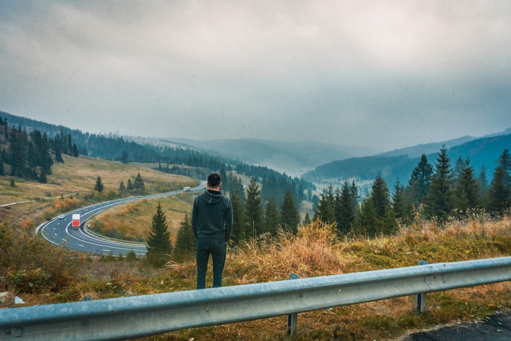 man in black jacket standing on gray concrete bridge during daytime