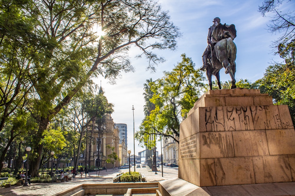 man riding horse statue near trees during daytime