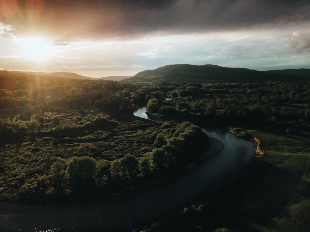 a river running through a lush green countryside under a cloudy sky