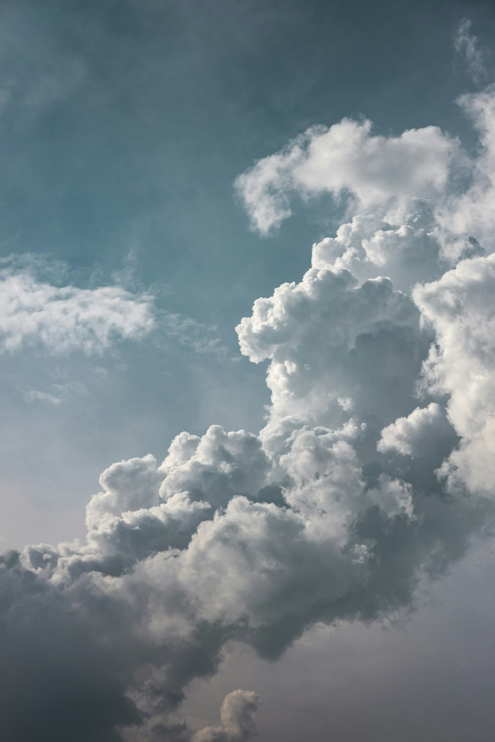 a plane flying through a cloudy blue sky