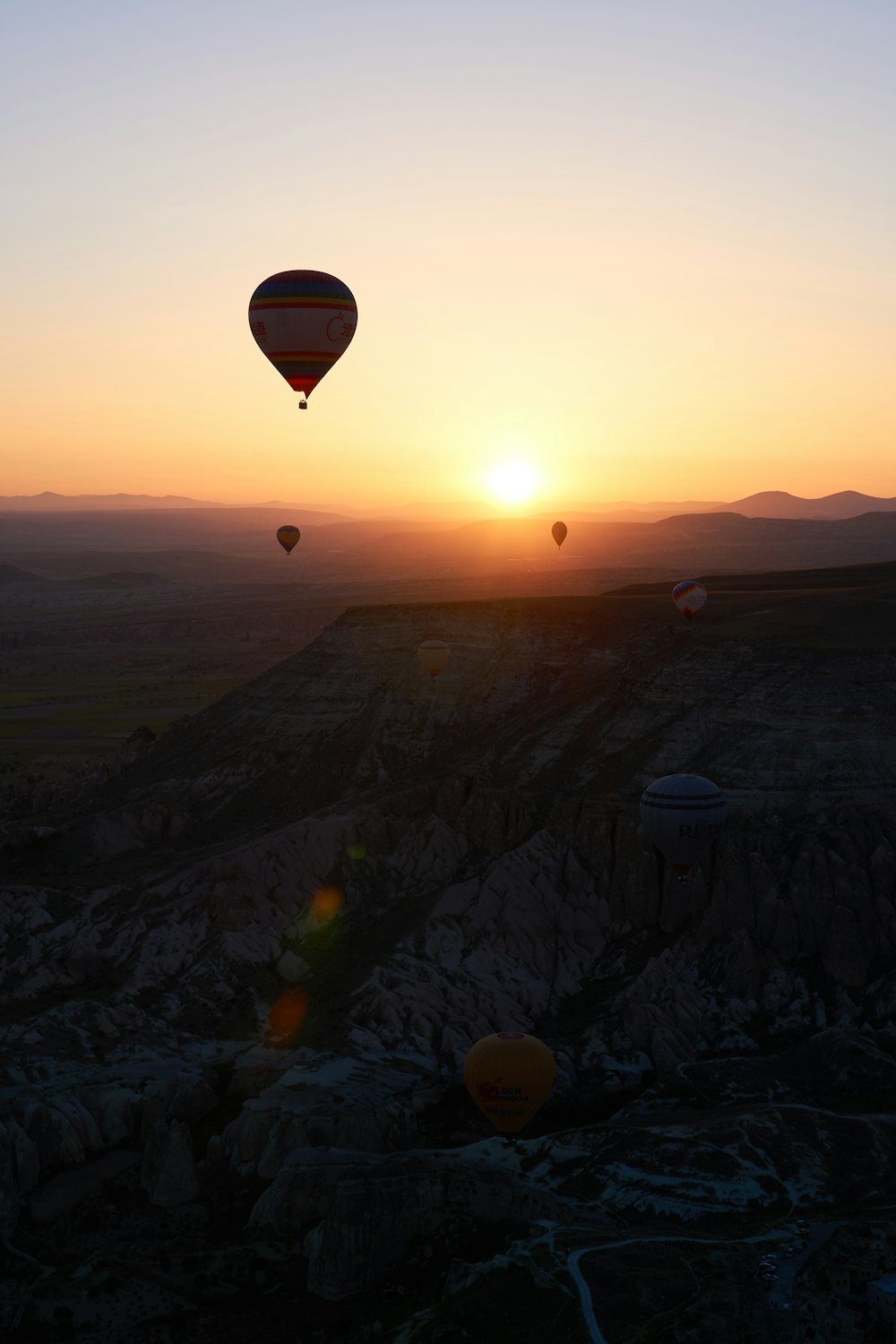 hot air balloons flying over the mountains during sunset