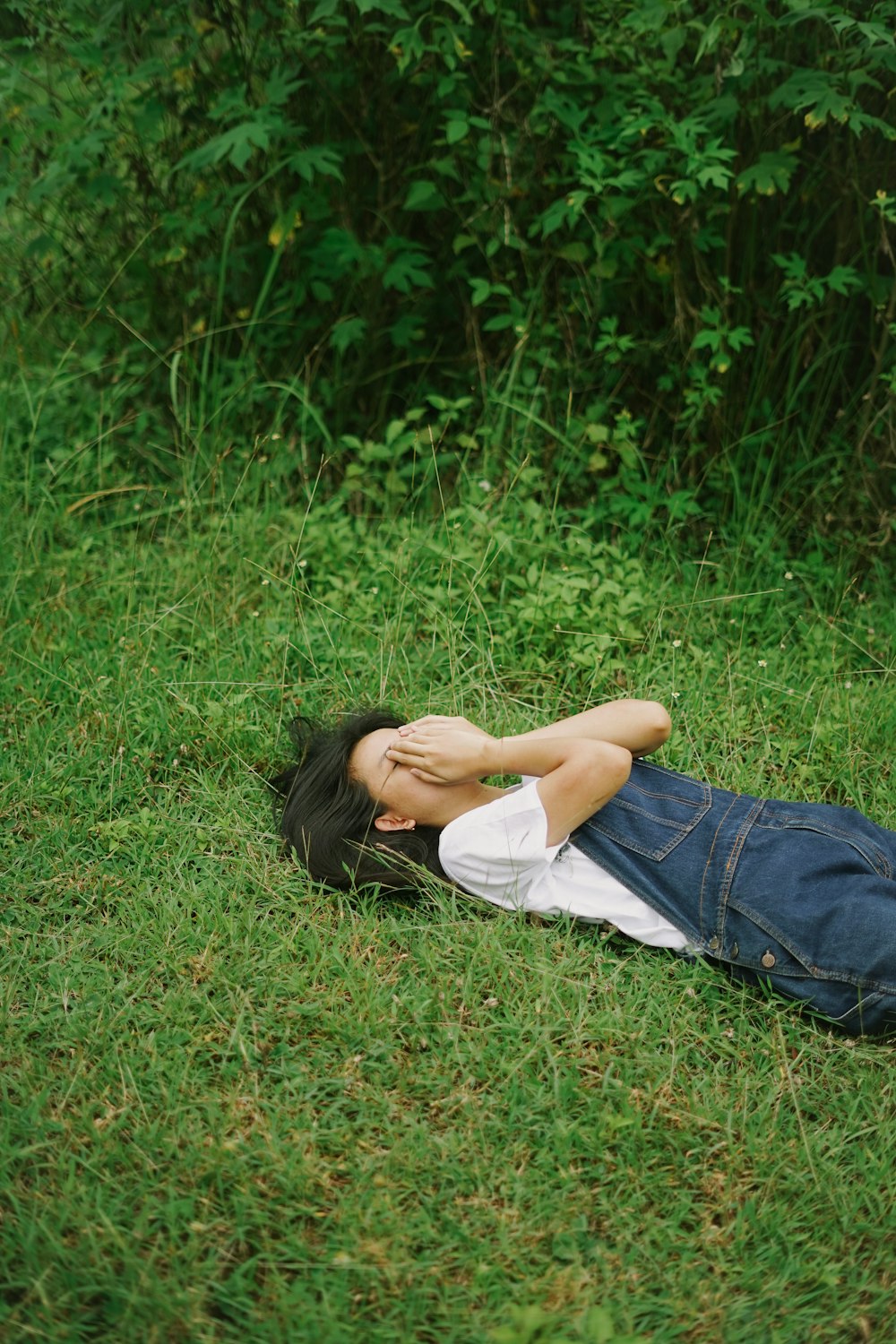 woman in white shirt lying on green grass field