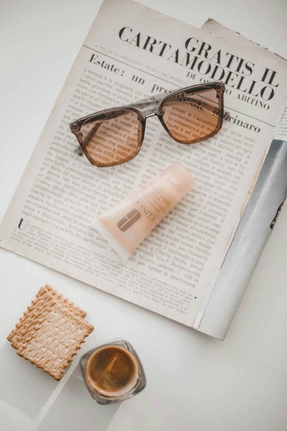 a newspaper with a cup of coffee and a pair of sunglasses
