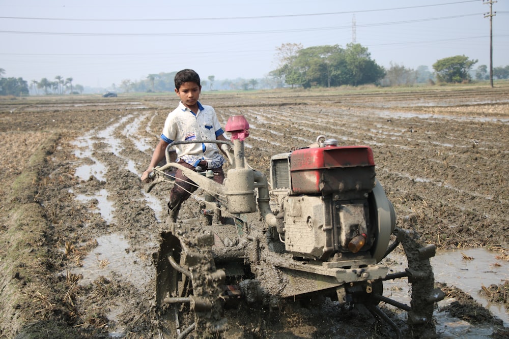 man in white t-shirt and blue denim jeans riding on red and black tractor during