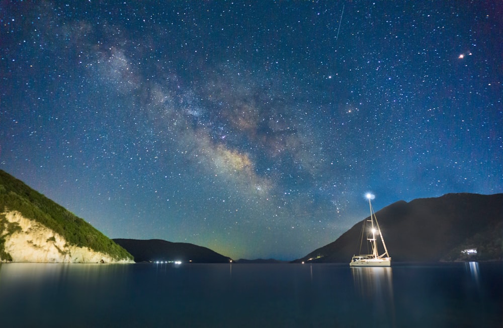 a boat in a body of water under a night sky filled with stars