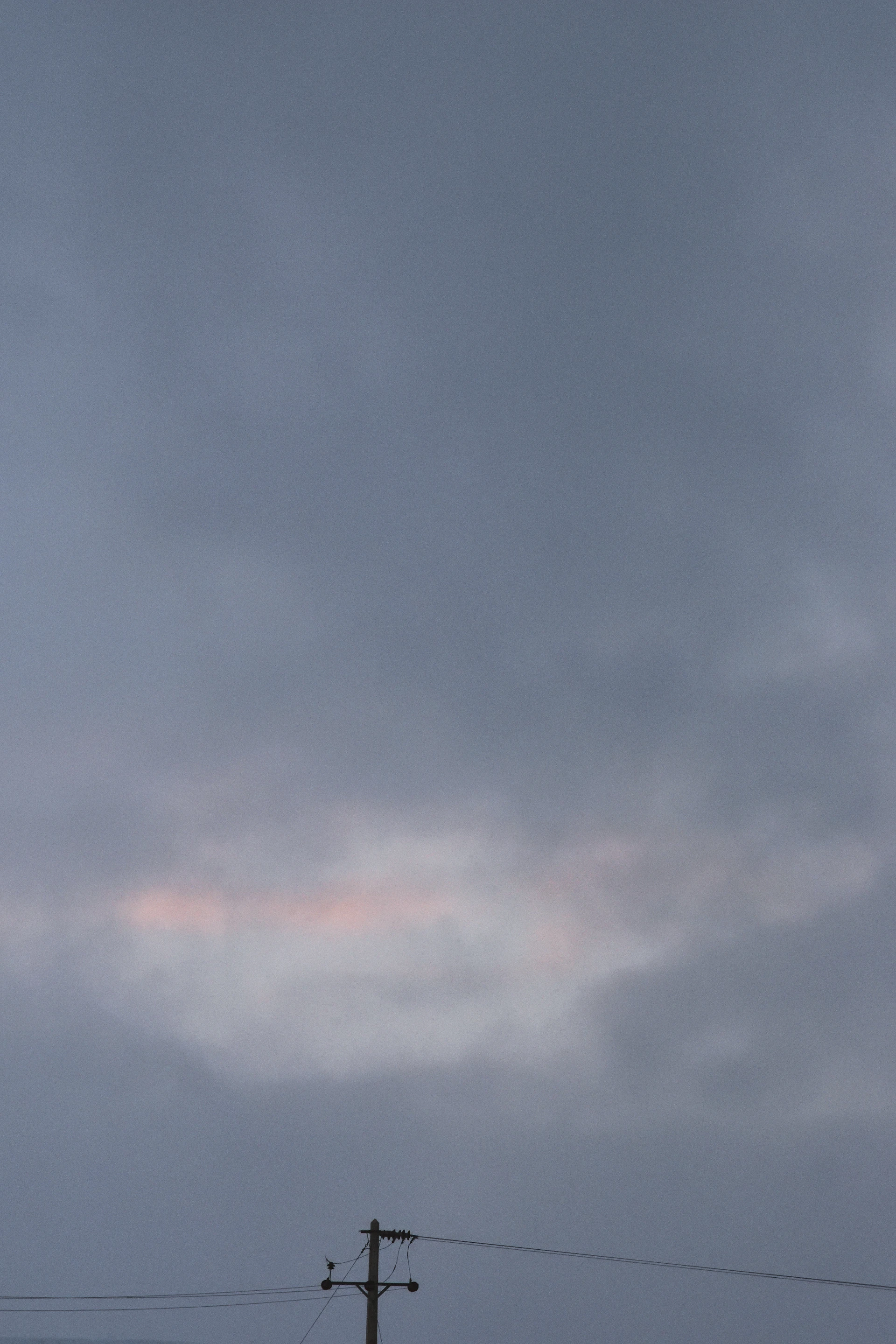 an airplane flying high in the sky with power lines in the foreground