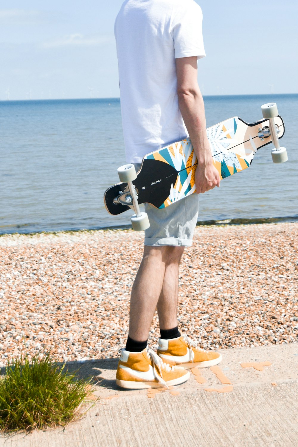 woman in white tank top and blue shorts holding black and white kick scooter during daytime