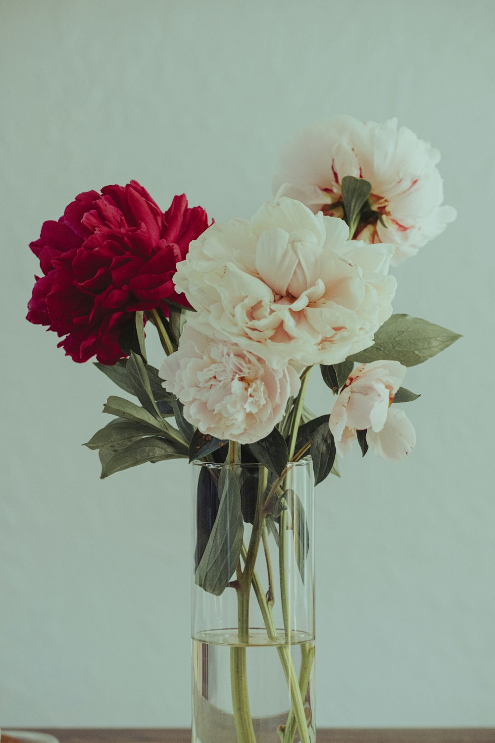 eine mit Blumen gefüllte Vase auf einem Holztisch