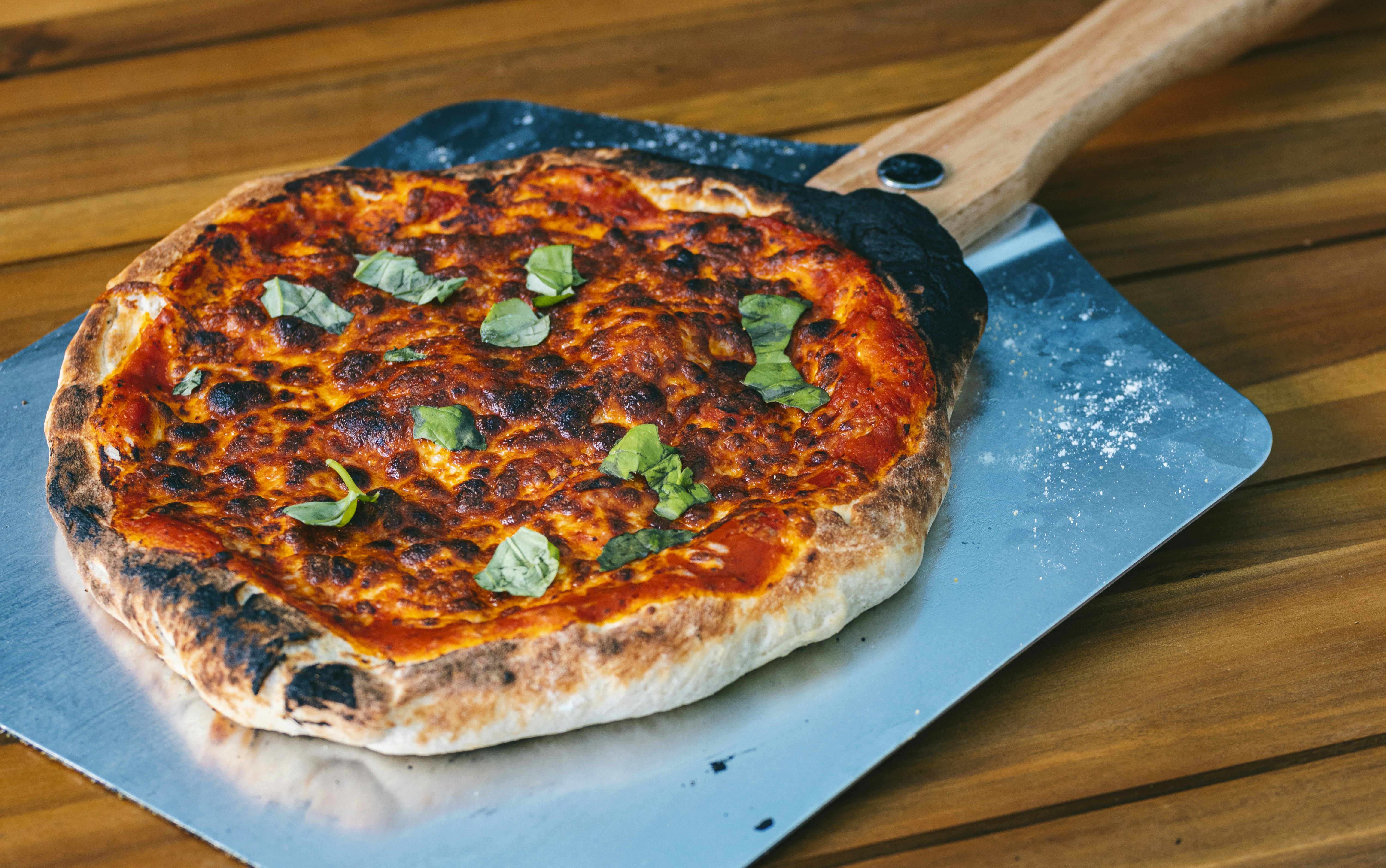 a pizza sitting on top of a pizza pan on top of a wooden table