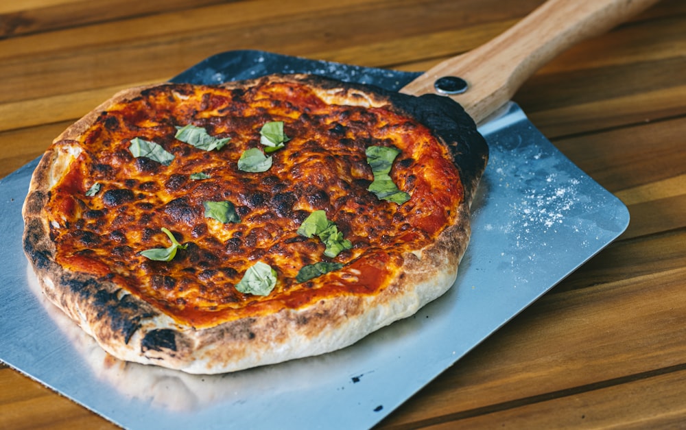 a pizza sitting on top of a pizza pan on top of a wooden table