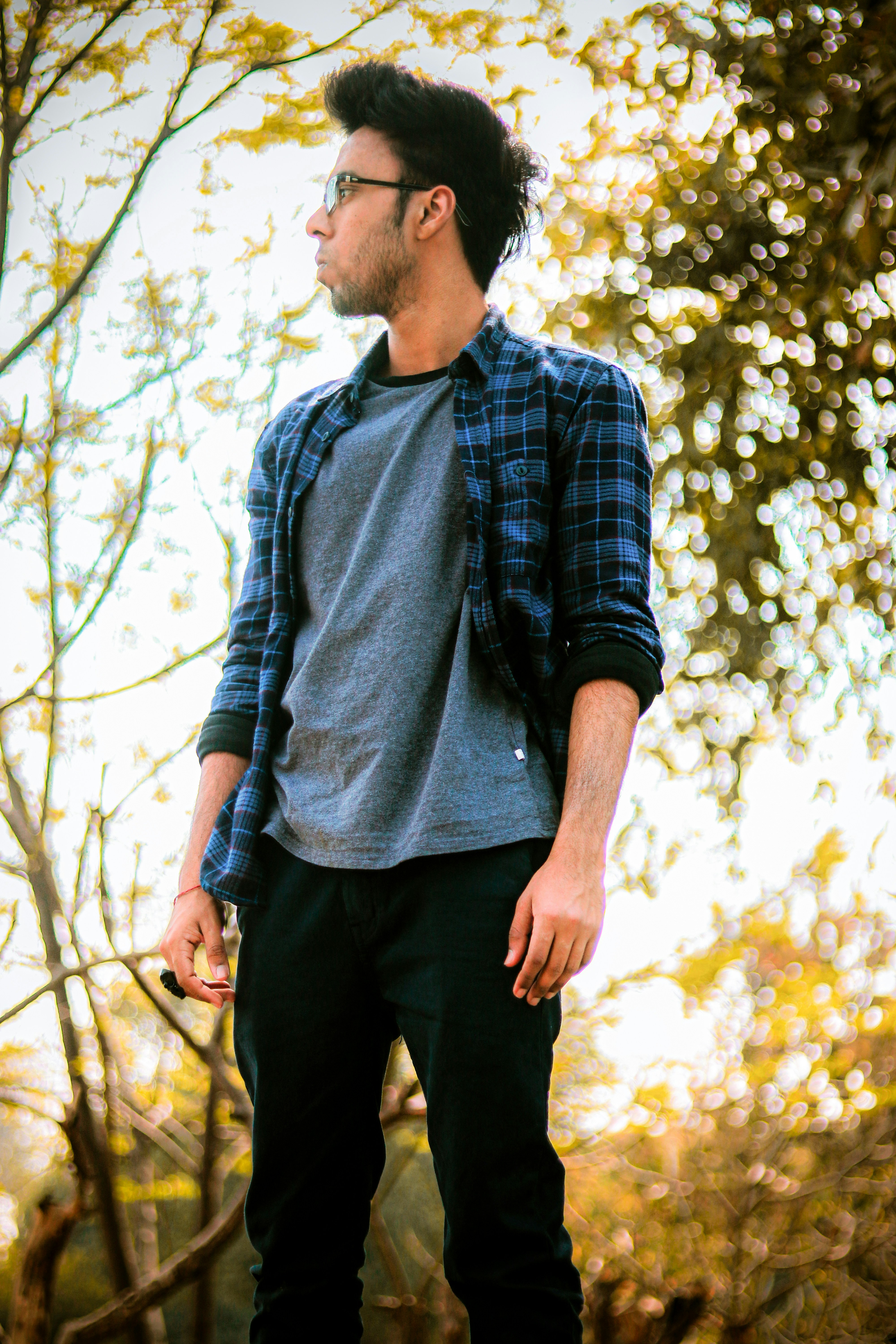 man in blue and white plaid dress shirt standing near trees during daytime