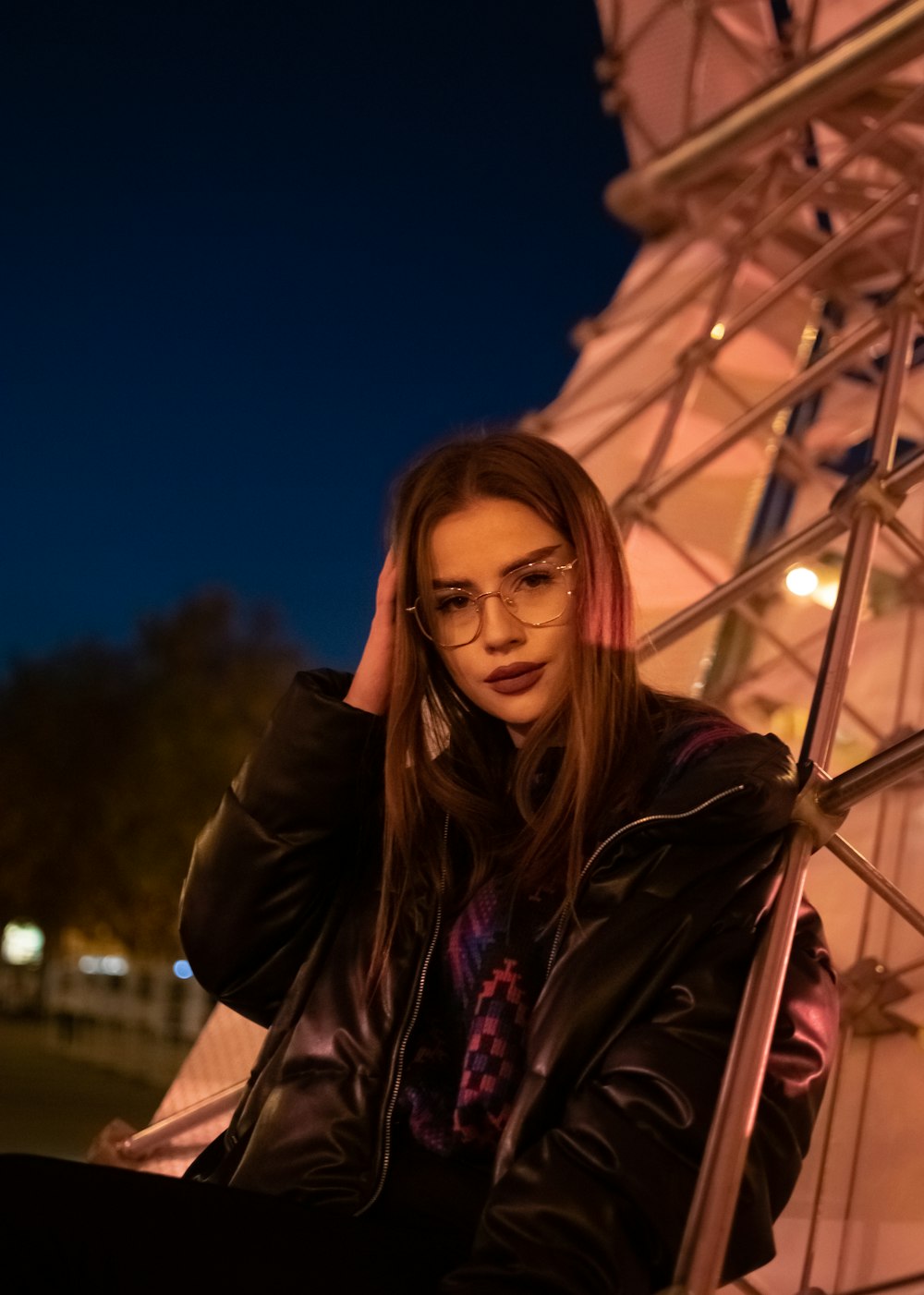 a woman in a black jacket leaning against a wall