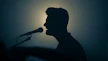 a silhouette of a man singing into a microphone