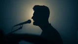 a silhouette of a man singing into a microphone