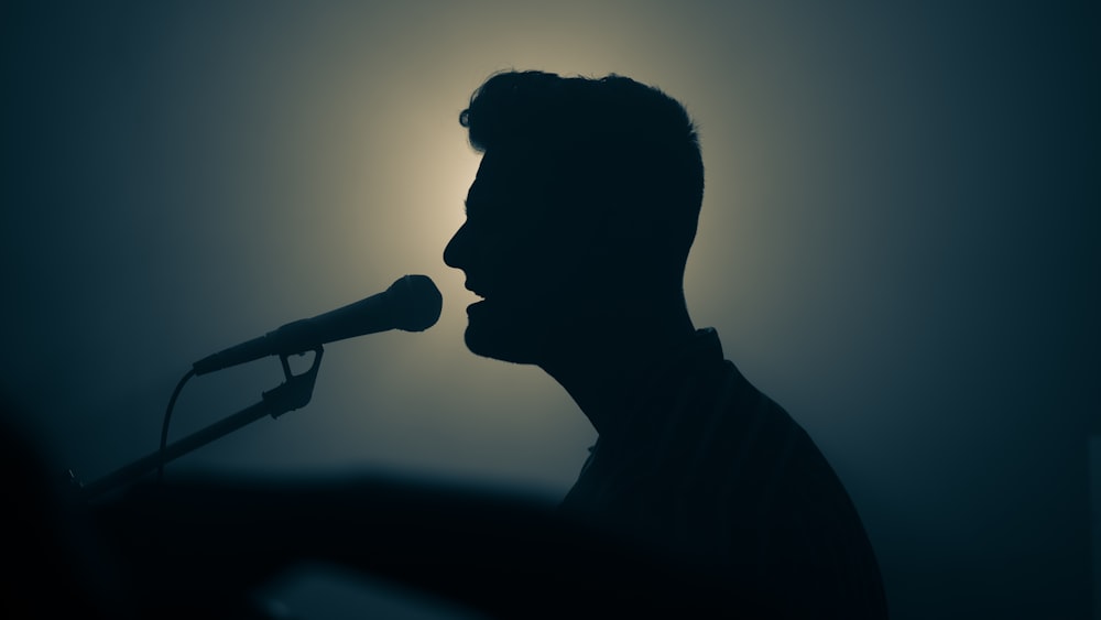 Silhouetted man singing into a microphone