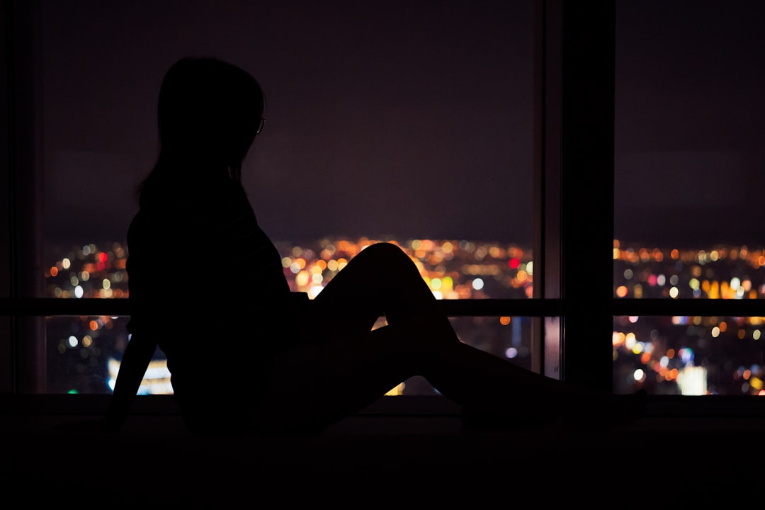 silhouette of woman sitting on window during sunset