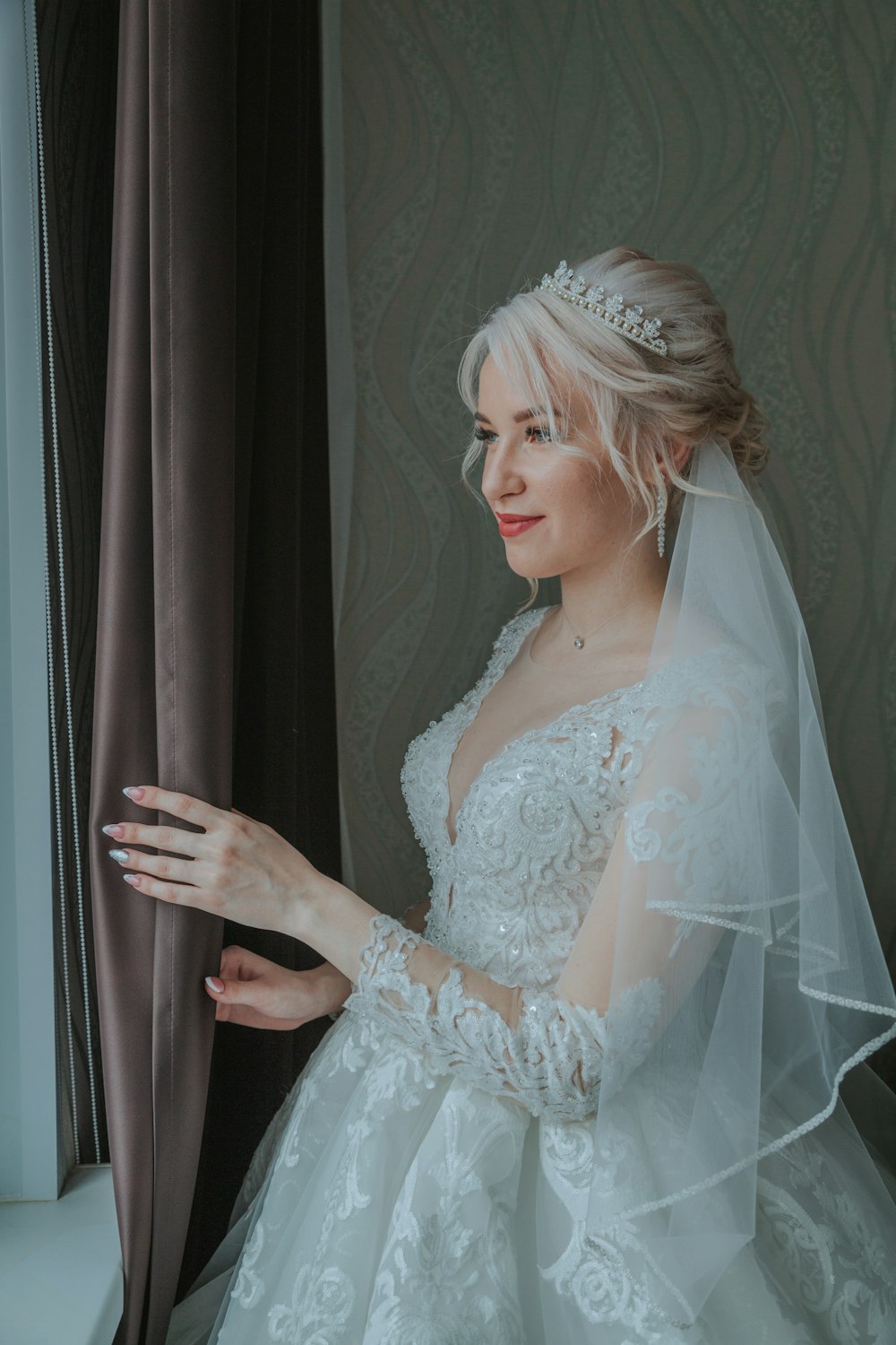 a woman in a wedding dress looking out a window