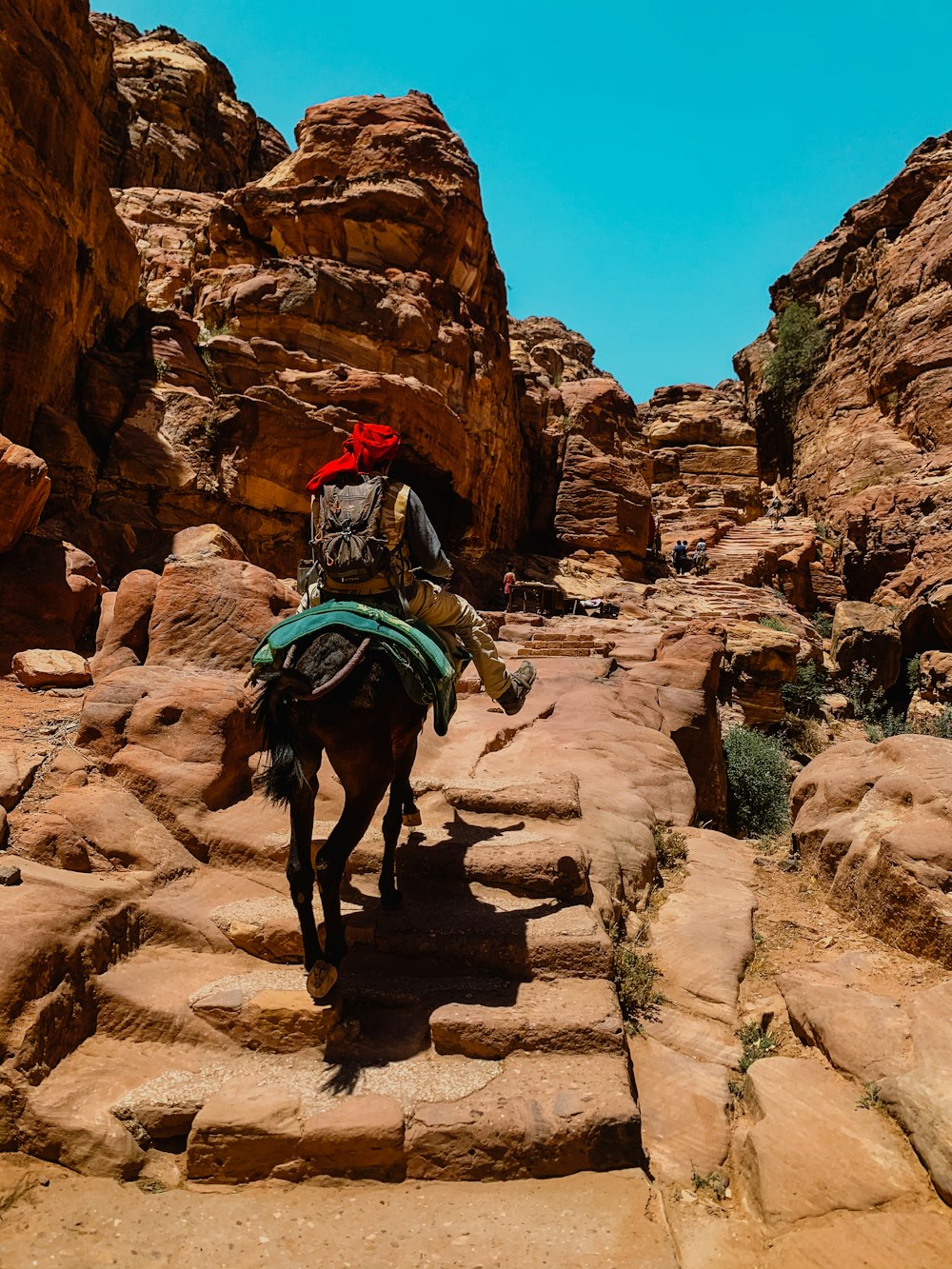 man riding horse on brown rock formation during daytime