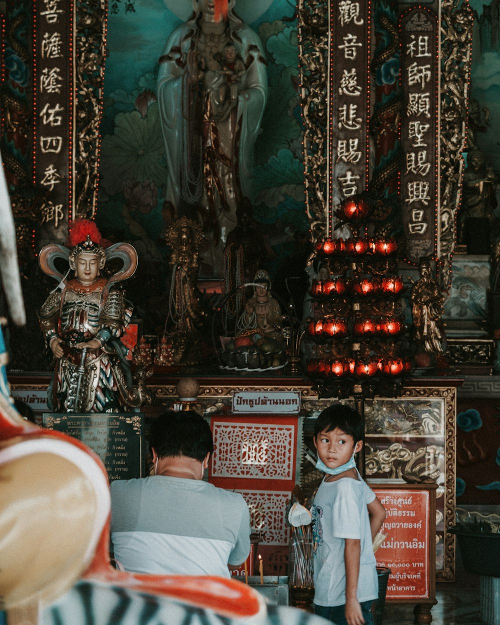 a little boy standing in front of a shrine