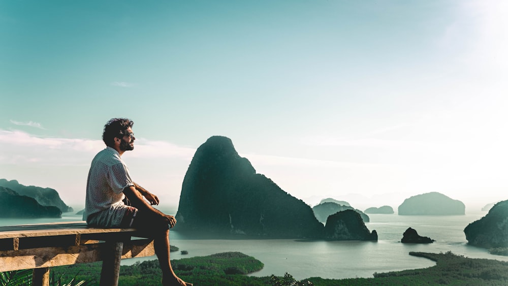 a man sitting on a bench looking at the ocean