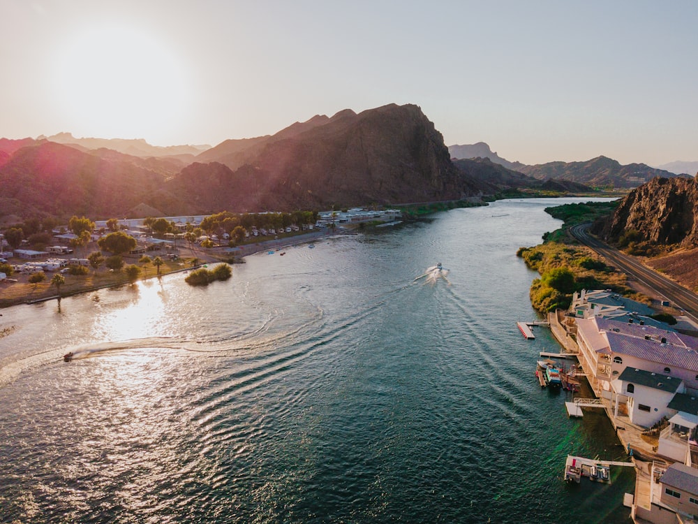 a boat traveling down a river next to a mountain range