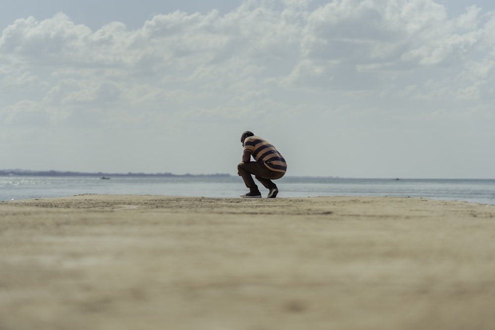 person in black and white striped long sleeve shirt and black pants sitting on beach shore