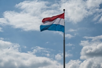 red and white flag under white clouds and blue sky during daytime